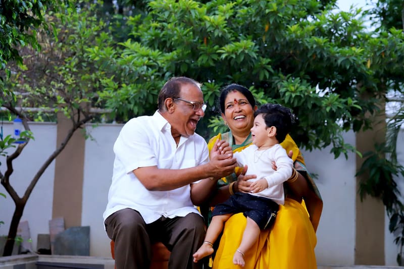 Grandparents laughing with their grandchild in a garden