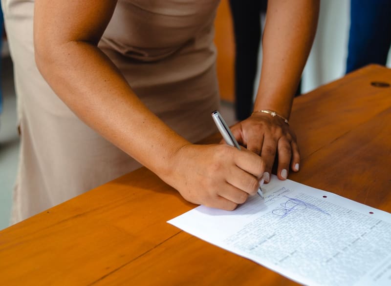 A woman signing a form at a wooden desk